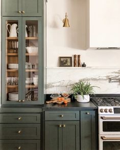 a kitchen with green cabinets and marble counter tops