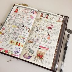 an open planner with stickers on it and a pen next to it, sitting on top of a table