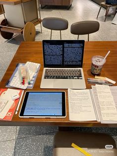 an open laptop computer sitting on top of a wooden desk next to a notebook and pen