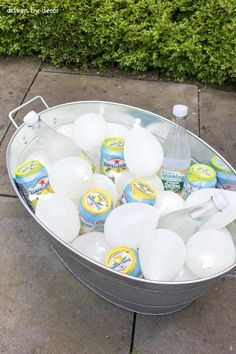 a bucket filled with lots of bottles of water next to a sidewalk on top of cement