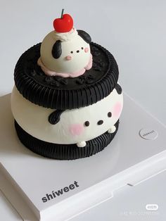 a cake shaped like a panda bear with a cherry on top is sitting on a white surface