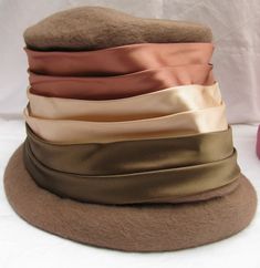 "The mark at the center of the underside of this hat shows it comes from Henry Pollack out of New York, and has the name \"Melosoie\" at the center. This is a light brown wool (probable) with felt lined hat with three different colors of satin wrap. The bottom color is a shiny army green, the center is a champagne or cream color, and the top is a copper color. The hat is 5 & 1/2\" tall. It measures 10\" from back to front, rim to rim. It measures 8\" from side to side, rim to rim." Green Champagne, Wrapped Lights, Long Tassel Necklace, Book Pieces, Cloche Hat, Saint Paul, Blue Rhinestones, Copper Color, Tri Color