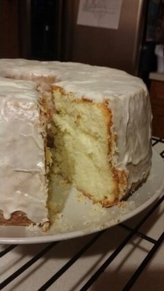 a cake with white frosting sitting on top of a cooling rack in a kitchen