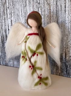 an angel figurine with white fur and green leaves on it's body