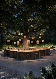 an outdoor dining area is lit up at night with paper lanterns hanging from the tree