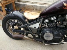 the motorcycle is parked on the side of the road in front of a wooden fence