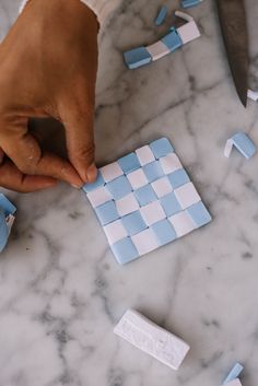 a person cutting up some blue and white tiles on a marble table with a knife