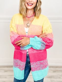 a woman standing with her arms crossed wearing a multicolored cardigan