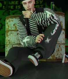 a man in striped shirt and black pants sitting on the ground with his legs crossed