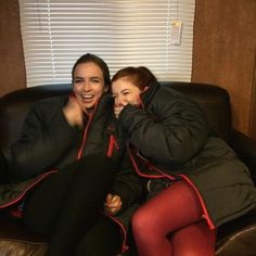 two people sitting on a couch with their arms around each other