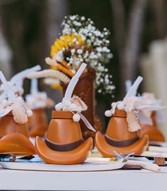 small brown hats with bows on them sitting on a table next to flowers and toothbrushes