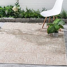 a white chair sitting on top of a rug next to a potted plant