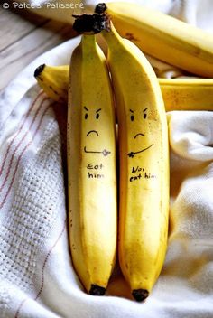 two bananas with faces drawn on them sitting next to each other in front of a white towel