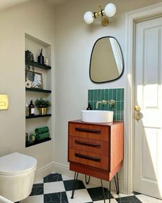 a white toilet sitting next to a wooden cabinet in a bathroom under a large mirror