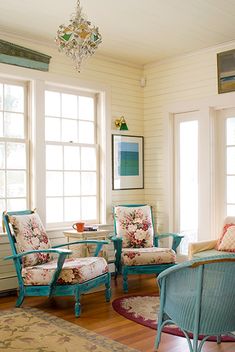 a living room filled with furniture next to two windows and a chandelier hanging from the ceiling