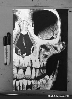 a black and white drawing of a skull on a piece of paper next to a pen