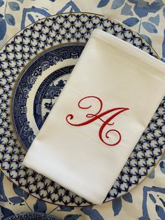 the monogrammed napkin is on top of an ornate blue and white dinner plate