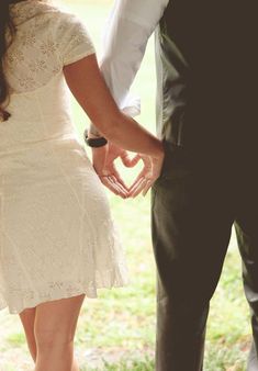 a bride and groom hold hands as they stand in the grass