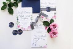 the wedding stationery is laid out with pink roses and blue envelopes on top