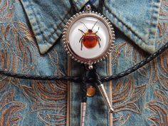 "We are a small independent company based in Derbyshire. We source our materials Worldwide to create something different and unique Our lovely Bolo ties are crafted/assembled by us in our workshop. This bolo tie has a genuine Flower bug set in clear resin . Every piece is crafted so there will be slight differences from the image in every one .  Silver colour metal trim and tips with a black leather cord standard length 36\" can be made shorter or longer if requested.Faux leather available.Sprin Men Boho, Boho Men, Dream Fashion, Bolo Ties, New Flower, Bolo Tie, Spring Steel, Bugs And Insects, Fedex Express