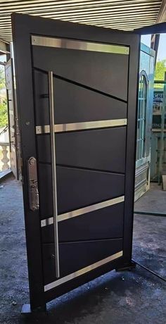 a black door with silver lines on the front and side panels is opened to reveal an entrance