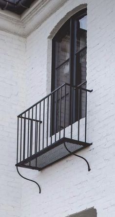 an iron balcony railing on the side of a white brick building