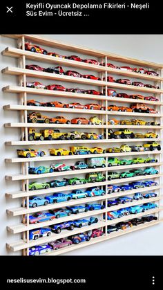 a wooden shelf filled with toy cars on top of a white wall next to a black and white sign