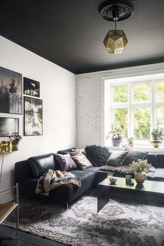 a living room filled with furniture next to a large window and lots of pictures on the wall