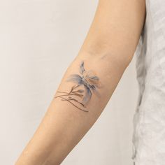 a woman's arm with a tattoo on it that has a bird sitting on the branch