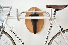 a bike with a wooden seat mounted to the side of it next to a coat rack