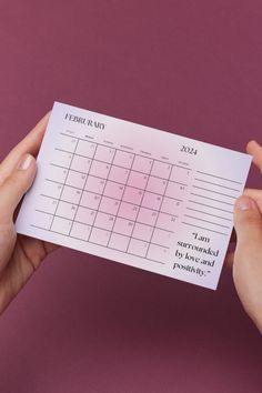 a person holding up a calendar on top of a piece of paper