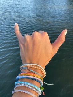 a person's hand with bracelets on the water