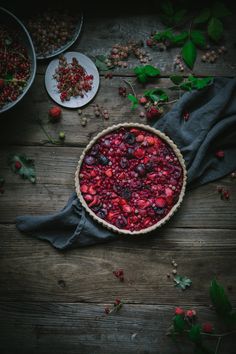 cranberry sauce in a pie pan on a wooden table surrounded by berries and leaves