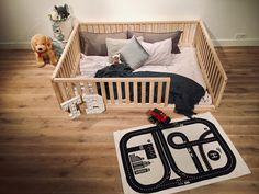 a baby's room with a toy train bed and teddy bear on the floor