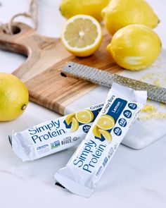 two bars of lemon protein sitting on top of a cutting board next to some lemons