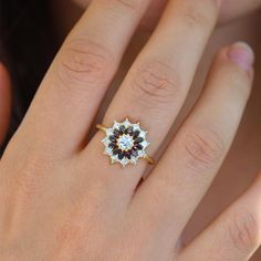 a woman's hand with a ring on it that has a black and white diamond in the center