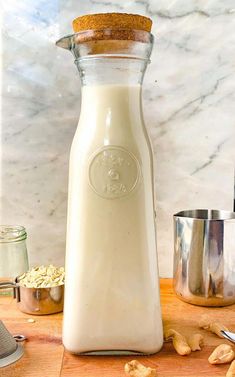 a glass bottle filled with milk sitting on top of a wooden table next to other items