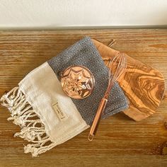 a wooden table topped with kitchen utensils next to a towel and whisk