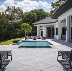 an outdoor swimming pool with lounge chairs around it and trees in the backgroud