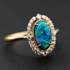 Engagement Ring: Australian Black Opal and Diamond in 18K Yellow Gold Free Domestic USPS First Class Shipping! Free Gift Bag or Box with every order! Opal—the queen of gemstones, is one of the most beautiful gemstones in the world. Every piece of opal is unique in its own ways and patterns. We only use high-quality Natural Opals (NO synthetics or imitations) for our jewelry. ----------------------------------------------------------------------------------------------------ABOUT THIS PRODUCTSolid 18K Yellow GoldAustralian Black Opal, 1.32 ct24 Diamonds: 0.222 ctOpal Body Tone: N4Opal Brightness: B4-B3Opal Size: 10 x 6 mmRing Size: 7Opal Color: Stnning green and yellow hues.Occasion: Engagement/Anniversary-------------------------------------------------------------------------------------- Formal Opal Rings With Gemstone Accents, Opal Ring With Diamond Accents For Formal Occasions, Formal Opal Ring With Gemstone Accents, Formal Opal Ring With Diamond Accents, Elegant Opal Ring With Gemstone Accents For Anniversary, Elegant Opal Cluster Ring With Gemstones, Luxury Yellow Gold Opal Ring With Accent Stones, Luxury Yellow Gold Opal Ring, Luxury Gold Opal Ring With Diamond Accents