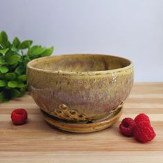 a brown bowl with some raspberries in front of it