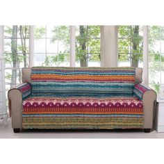 a multicolored couch sitting in front of two windows