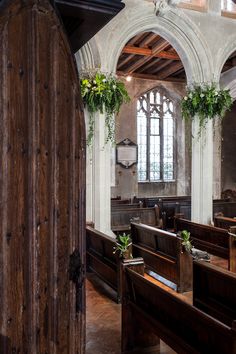 the interior of an old church with wooden pews and plants hanging from the ceiling