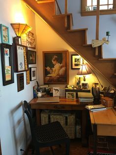 a home office under the stairs with pictures on the wall and desk in front of it