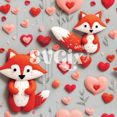 two red fox brooches sitting next to each other on a gray surface surrounded by hearts