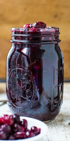 cranberry sauce in a mason jar with spoons on the table next to it