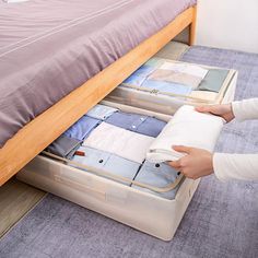 the woman is packing clothes in her suitcase on the floor next to the bed and dresser