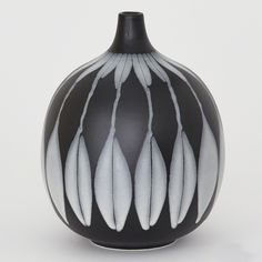 a black vase with white feathers on it