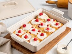 a baking dish with cream and raspberries in it next to a glass of milk