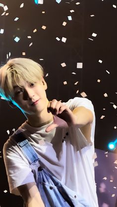 a young man with blonde hair and white shirt holding a microphone in front of confetti